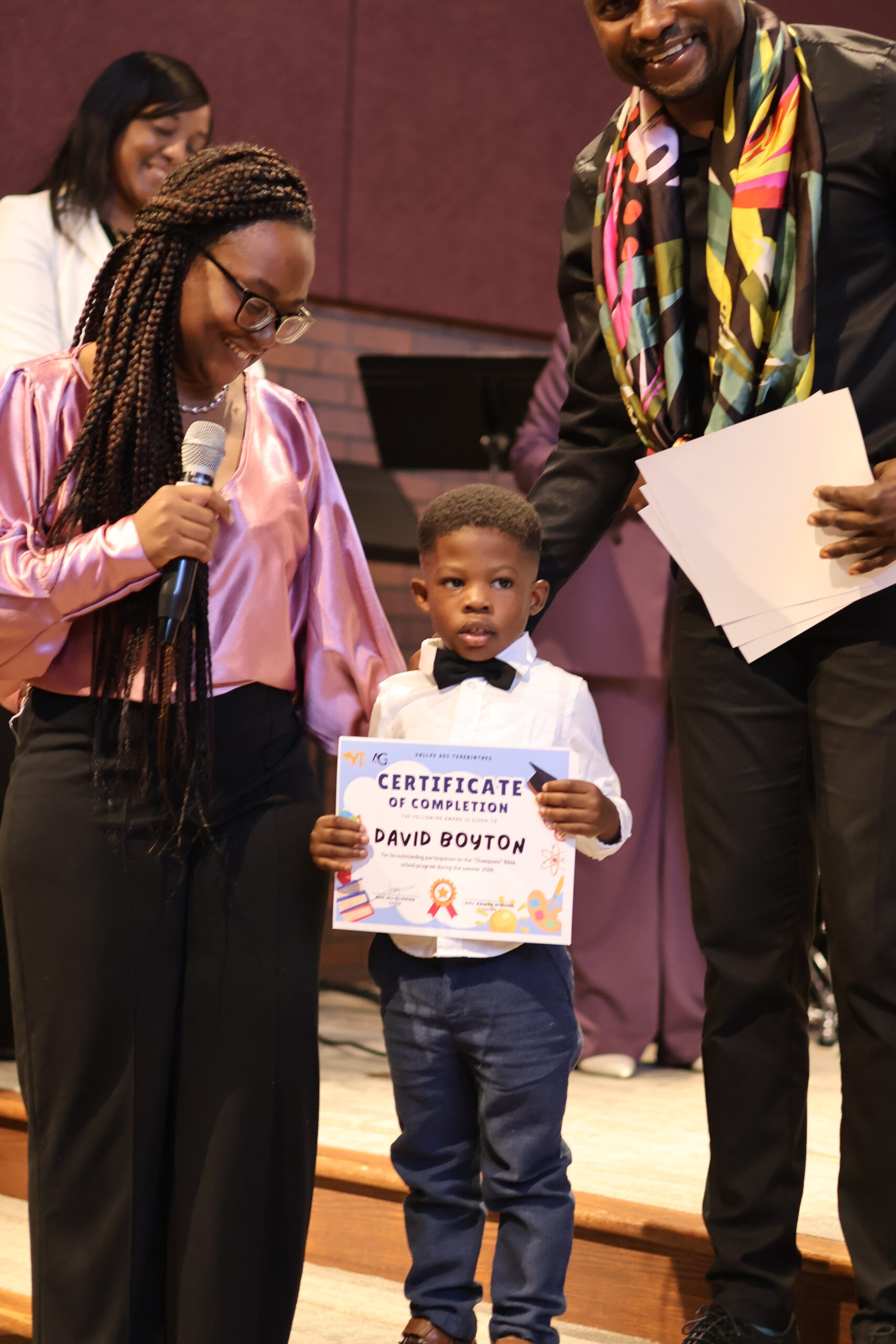 A young participant receiving a summer school certificate